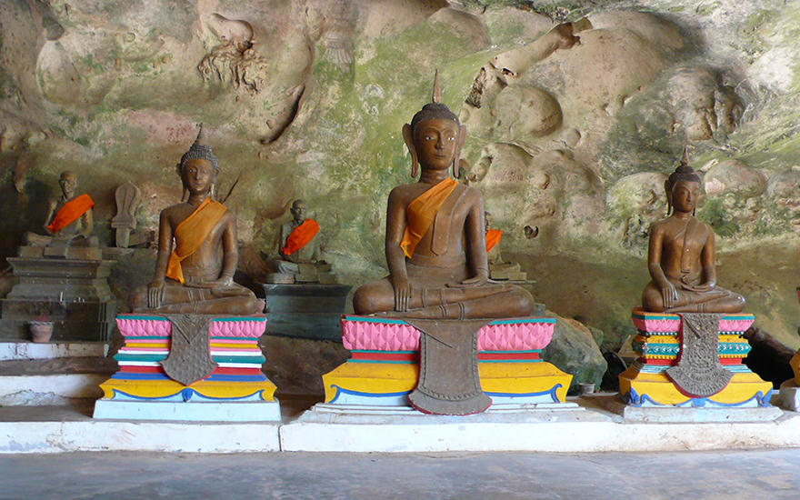 Buddha-Statuen auf bunten Sockeln im Höhlentempel Wat Suwan Kuha