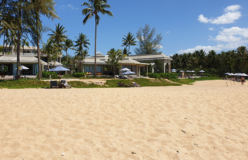 Beach-Bungalows des Devasom Khao Lak Beach Resorts mit viel Glas und hellen Dächern