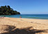 Sunset Beach in Khao Lak mit goldgelbem Sand und bewaldetem Hügel am Ende der Bucht