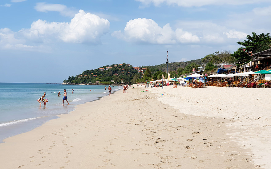 Klong Nin Beach auf Koh Lanta – langer Sandstrand mit Beach-Bars, Menschen und bewaldetem Hügel mit Bungalows