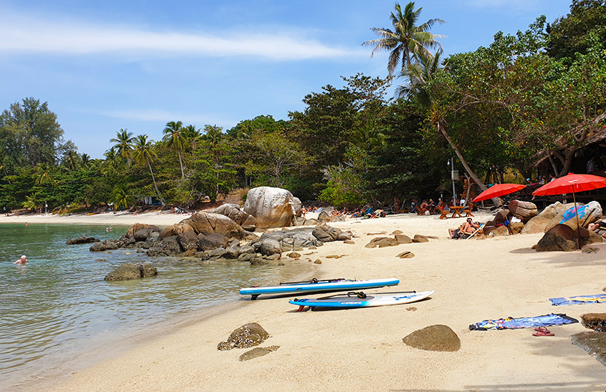 Sunset Beach auf Koh Lipe mit Felsen und dichtem Grün am Ufer