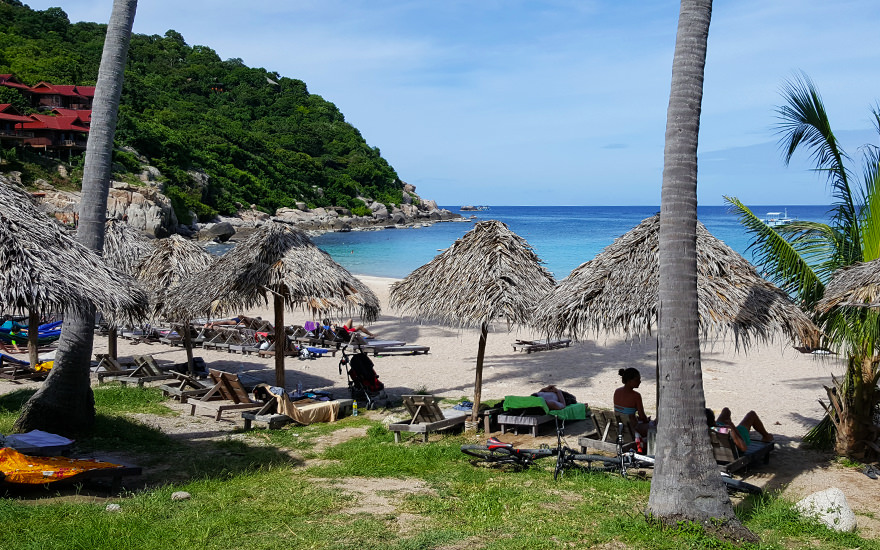 Ao Leuk – Strand mit Sonnenschirmen aus Palmwedeln, Liegen und türkisfarbenem Wasser