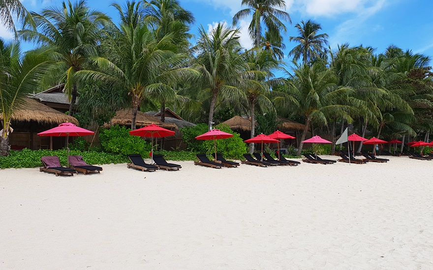 Bungalows am Thong Nai Phan Noi Beach mit weißem Sand, Palmen, roten Sonnenschirmen und Strandliegen aus Holz