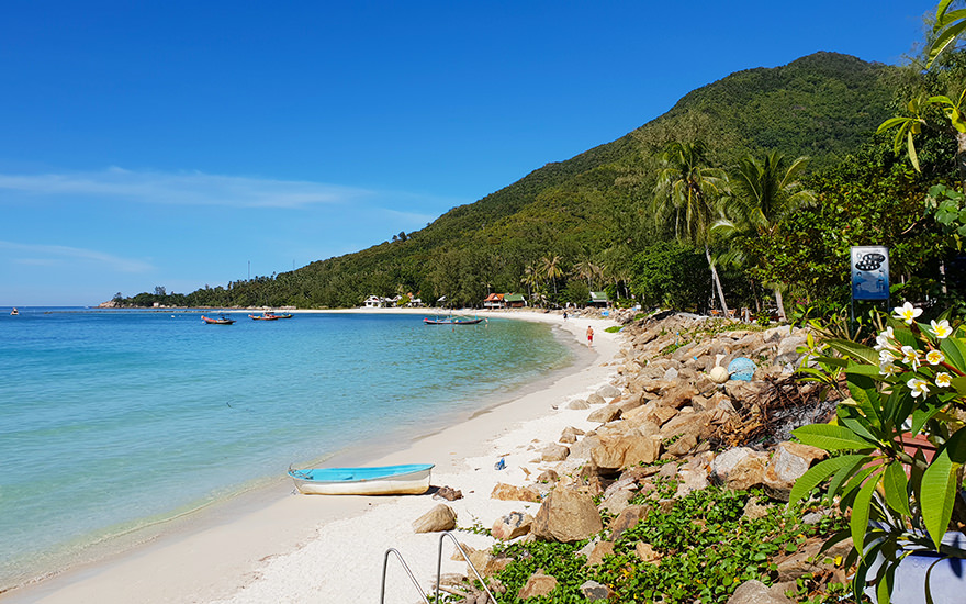 Caloklum Beach – geschwungene Bucht mit türkisfarbenem Wasser, Felsen, Palmen und bewaldeten Hügeln