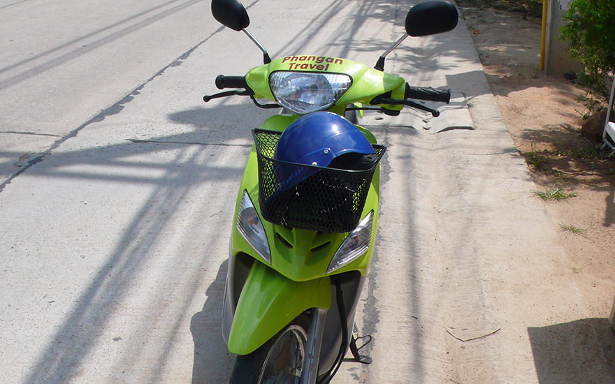 Hellgrüner Roller mit blauem Helm im Lenkradkorb auf einer Straße auf Koh Phangan