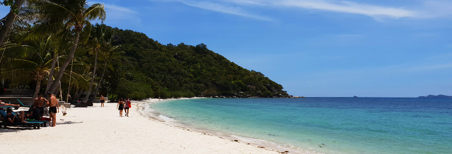 Leela Beach auf Koh Phangan mit weißem Sand und türkisfarbenen Meer bei Sonnenschein und beinahe wolkenlosem Himmel