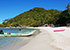 Haad Khuat (Bottle Beach) auf Koh Phangan mit weißem Sand, Longtailboot und bewaldeten Hügeln