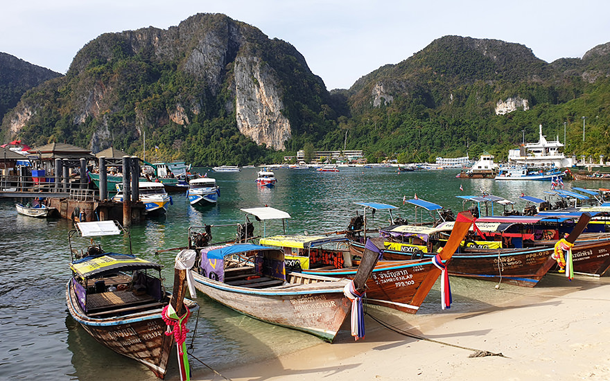 Tonsai Bay auf Koh Phi Phi mit Longtailbooten und teils bewaldeten Kalksteinfelsen