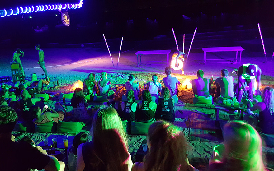 Abendliche Feuershow am bunt angestrahlten Sairee Beach mit im Sand sitzenden Besuchern