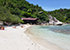Freedom Beach auf Koh Tao mit weißem Sand, Bäumen, Menschen und glasklarem Wasser, dahinter bewaldete Hügel mit Felsen