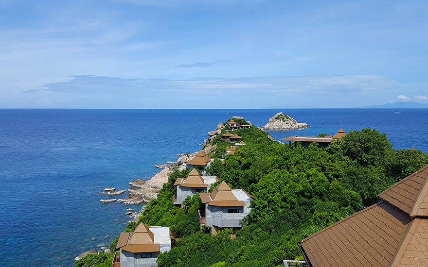 Bungalows mit braunen, spitzen Dächern auf bewaldeter Klippe am Sai Daeng Beach