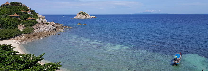 Sai Daeng Beach mit in allen Türkis- und Blautönen schimmerndem Meer und grünen Hügeln mit Bungalows