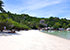Shark Bay auf Koh Tao – weißer Sandstrand mit kleinen Bäumen am Ufer, Booten im Wasser und Resort am Strandende